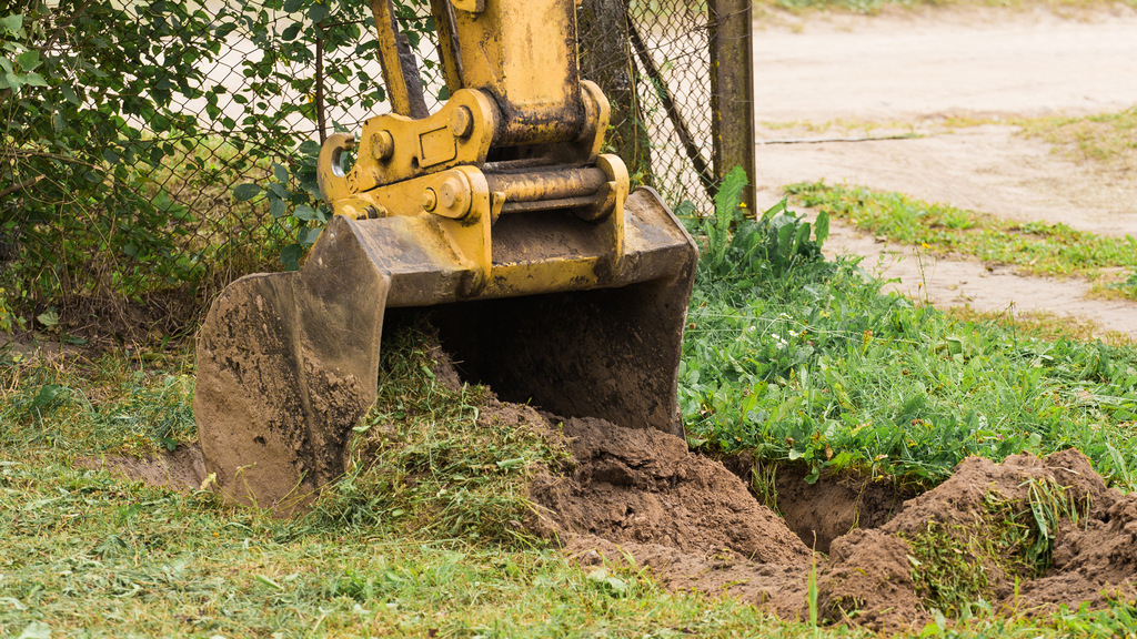 Grävskopa gräver upp gräsmatta på en privatpersons tomt.