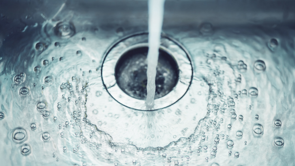 I en diskho i rostfritt stål rinner en vattenstråle.